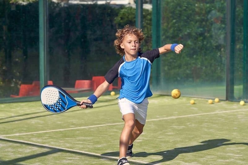 Enfant jouant au padel avec une raquette bleu
